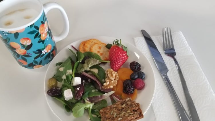 Coffee and plate of salad, olives, cheese, fruit and crackers with coffee